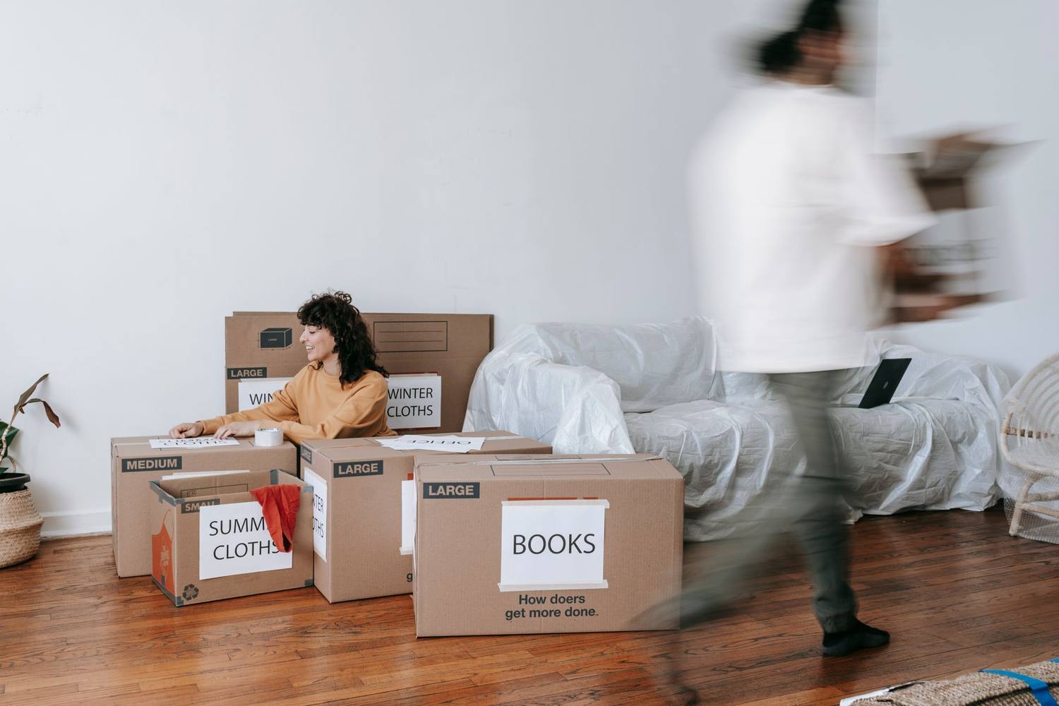 Un couple empile des cartons étiquetés dans un salon minimaliste, se préparant pour le jour du déménagement.